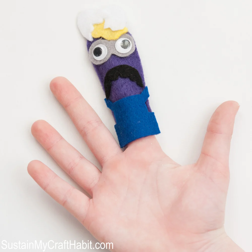 Purple minion felt finger puppet on a child's open hand