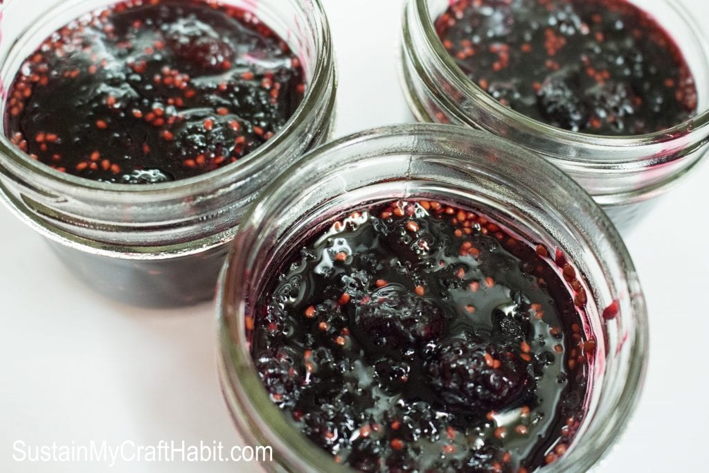 Three small glass ja jars filled with completed mulberry jam.