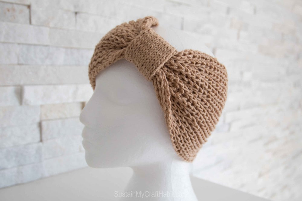 A knitted headband from a cowl knitting pattern on a mannequin head.