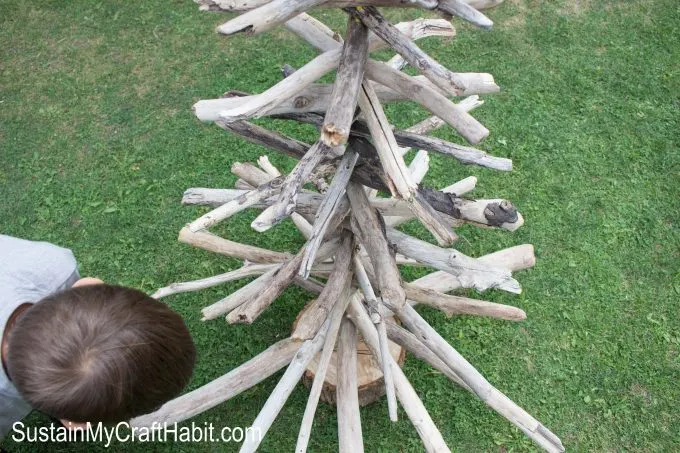 Child looking at different pieces of their Christmas tree made with driftwood branches
