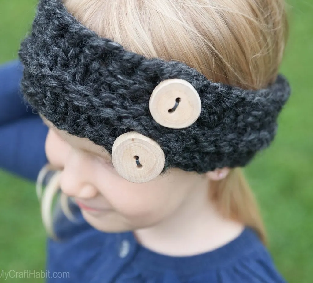 A child wearing a knitted headband made from a free pattern and embellished with handmade wood buttons
