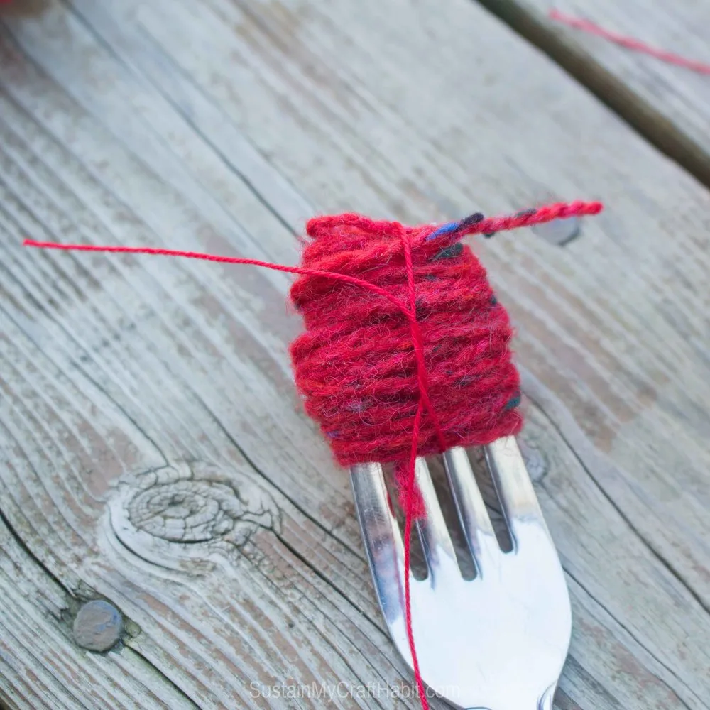 Tying together the wound red yarn to create the pompom.