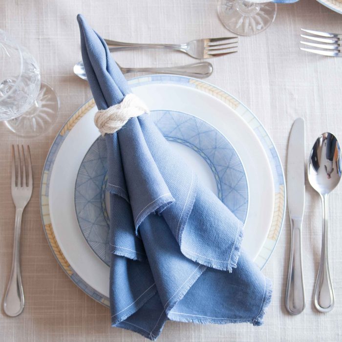 DIY Irish linen napkins with a frayed hem finish and nautical-inspired sailor-cable napkin rings. A step-by-step tutorial is included as well as a video for making the napkin rings. These would be perfect for any coastal or nautical themed event such as a dinner party, wedding reception or shower. Click through for all the details as well as links to 11 other crafts you can make with 1 yard of fabric.