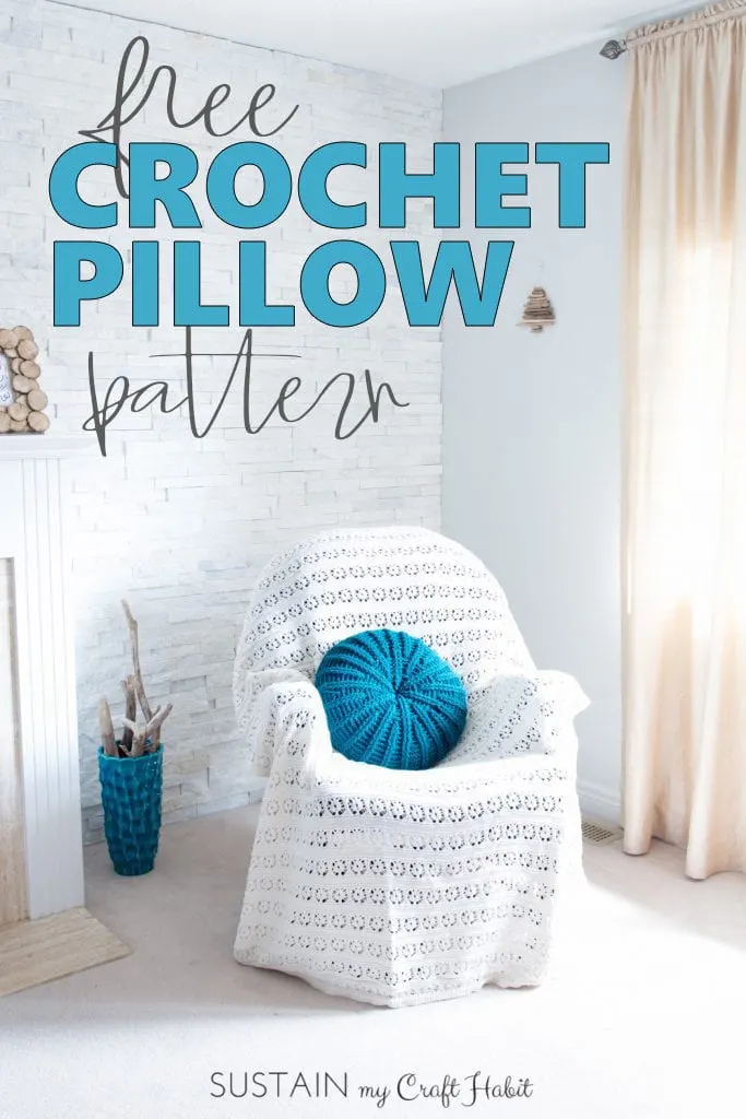 A teal, round crochet throw pillow on a chair covered with knitted white throw in the corner of bright white bedroom.
