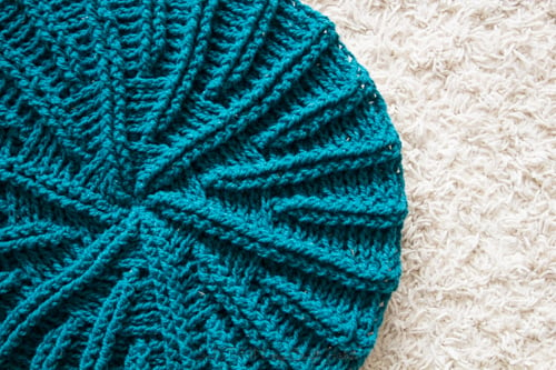 Image of the crochet pillow cover pattern made with teal wool yarn which looks like a sand dollar