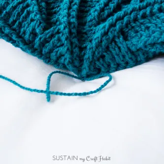 Close up image of tying off the yarn ends to create the pucker in the coastal throw pillow pattern
