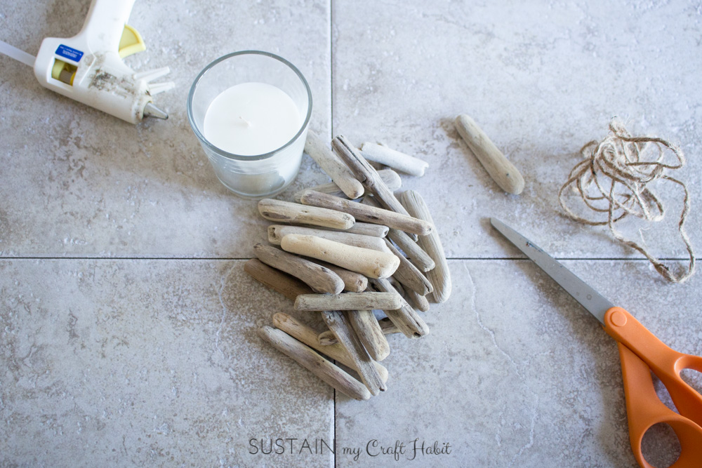 Materials needed to make the driftwood candle holder laid out on a ceramic tile floor.
