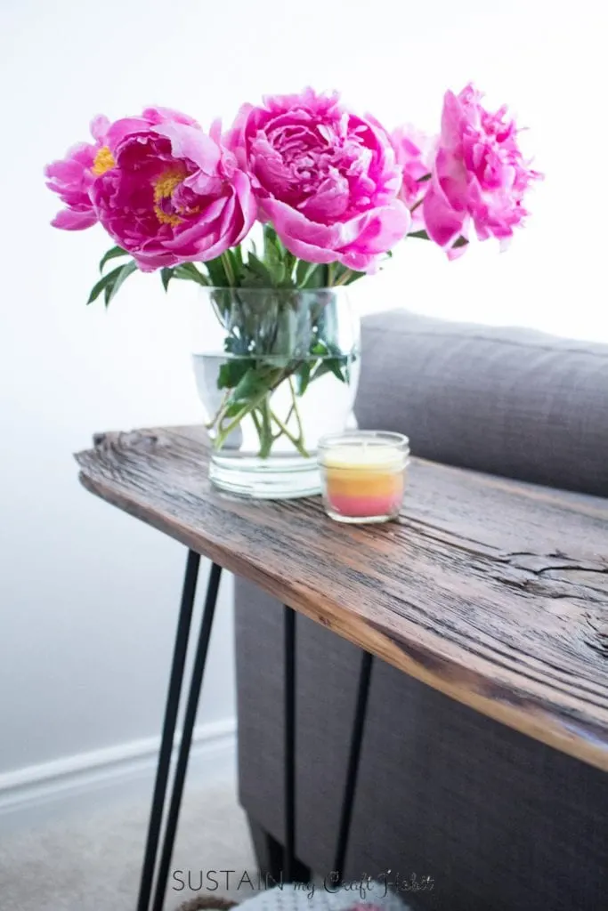 Vase filled with pink peonies adorns a DIY console table made with barn board and hairpin legs