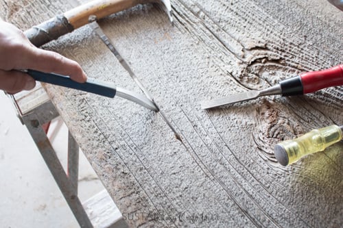 Using tools to pry away a crached piece of barn board to make a 12" wide DIY console table