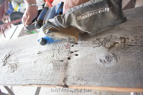 Sanding a piece of barn board with a belt sander