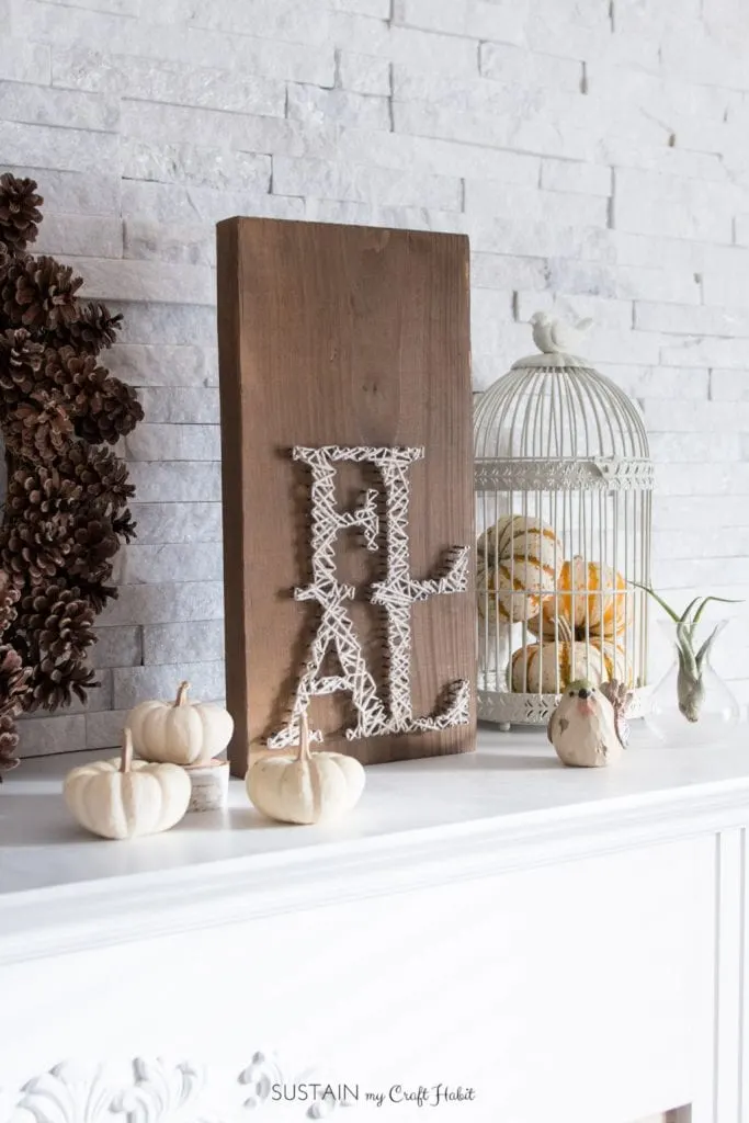 A fireplace mantle style with a farmhouse barn board fall string sign and neutral white pumpkin decor