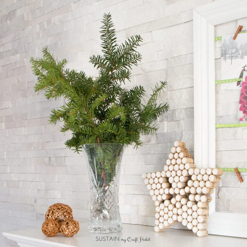 Rustic holiday mantel including foraged winter green branches and a sparkling star made from wine corks. #winecorkcrafts #winecorks #Christmasdecor