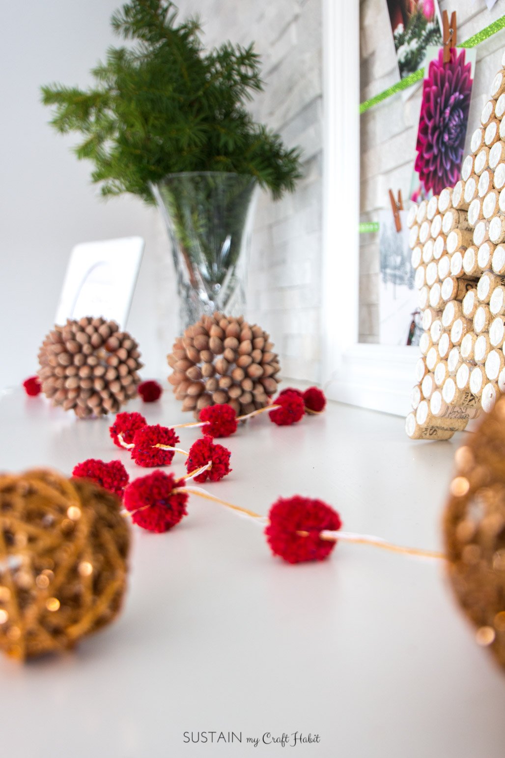 Red DIY pom pom garland on a fireplace mantel at Christmas.