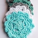 Teal, white and gray crochet coasters on a white surface