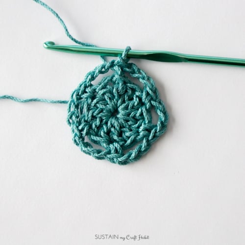 Completing the second round for a crochet coaster made with teal cotton yarn