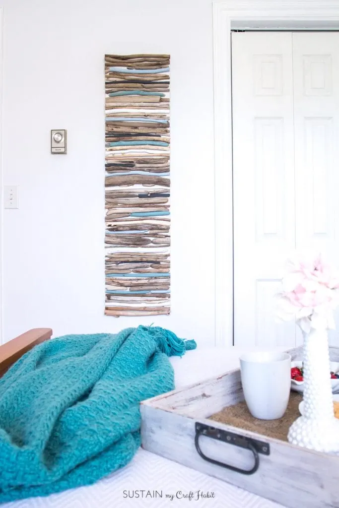 Create a beautiful coastal art piece for your wall using driftwood and a cool mix of blues, white and grey paint.