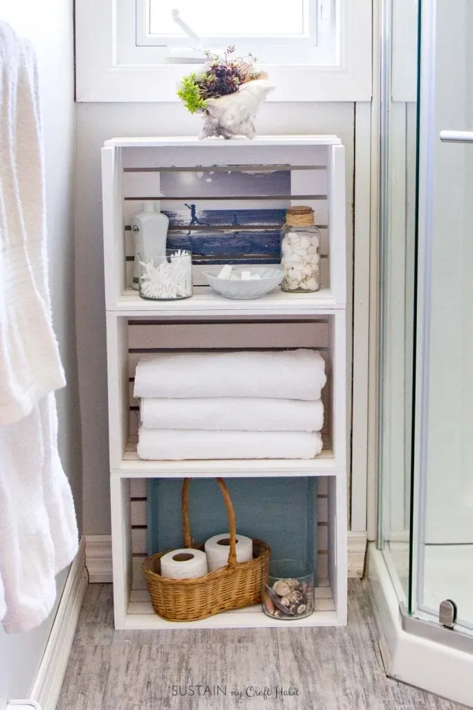 White washed stacked crate storage unit for a small, coastal style bathroom.