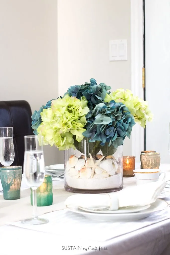 So beautiful! A summer tablescape including a DIY beach theme centerpiece with sea shells and hydrangeas from Afloral.com . Video tutorial included for this beach themed wedding, bridal shower or coastal cottage decorating idea! [sponsored]