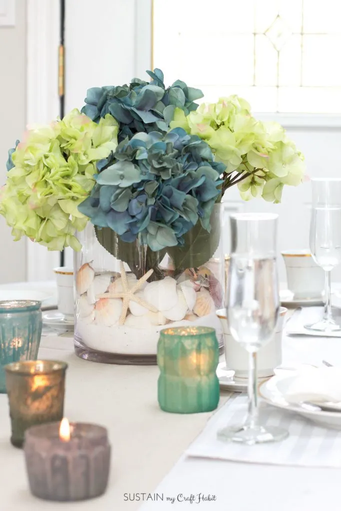 Learn how to make this simple beach theme centerpiece with sand, sea shells and hydrangeas. Video tutorial included!