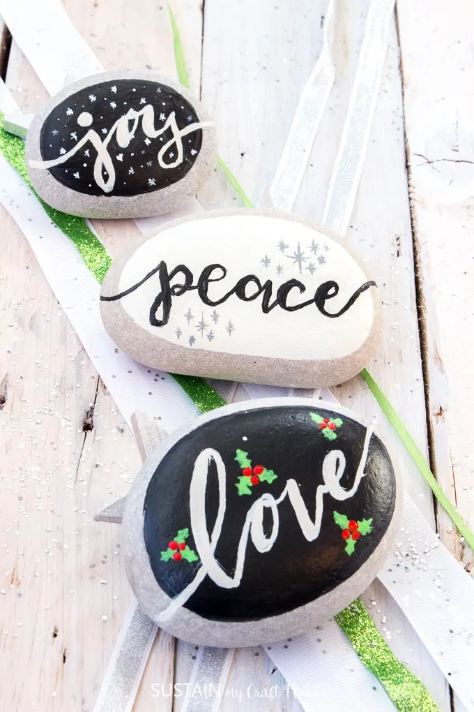 Over a dozen Christmas Rock Painting Ideas including Love, Peace, Joy! Rock painting Christmas holidays | Canadian bloggers craft hop | #christmascrafts #rockpainting #rusticchristmas | step-by-step DIY rock painting tutorial for beginners | Festive painted beach stones