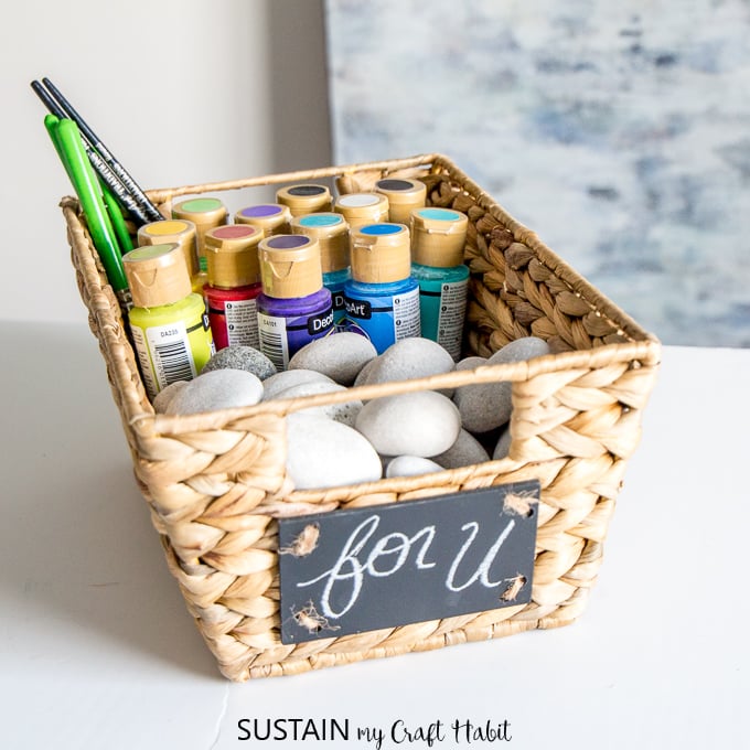 Basket fulled with rocks and paints as an example of a rock painting kit.