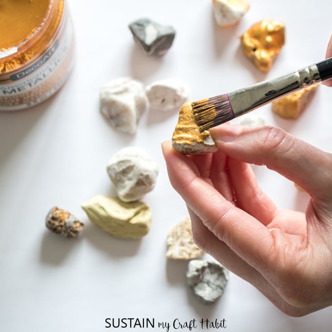 Painting a rock with gold paint.