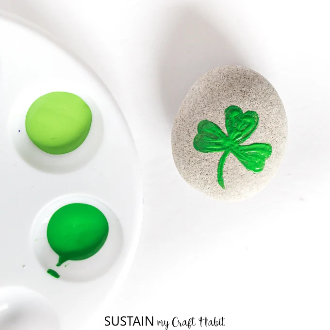 Painting the first layer of the shamrock on a round grey beach stone.
