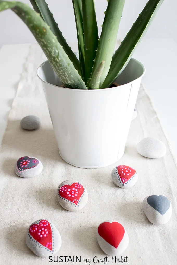 set of painted heart rocks on a burlap table runner