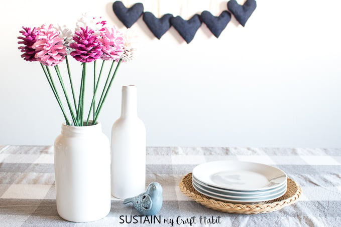 Bouquet of pine cone roses on a dinner table with a heart banner in the background