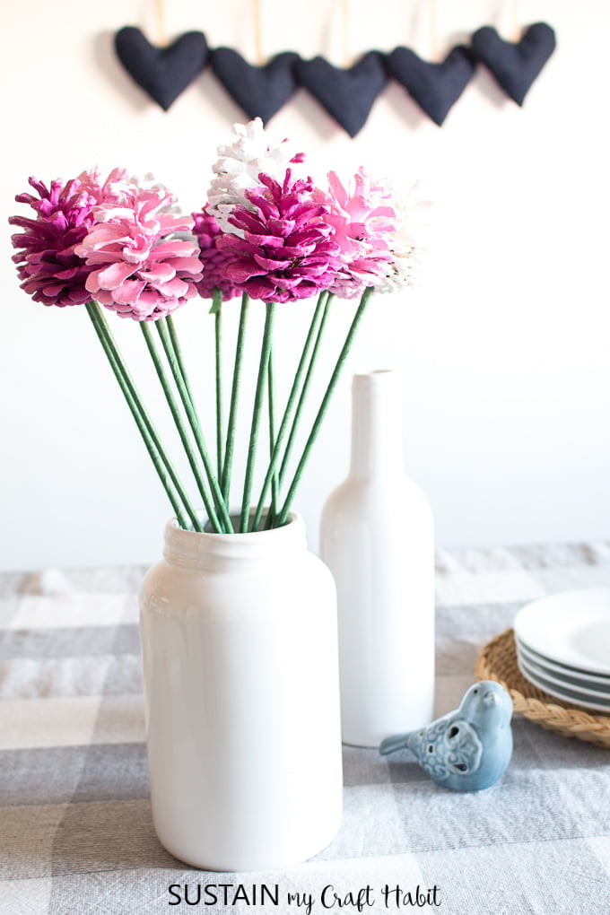 A bouquet of pink and white pinecone roses in a white porcelain container of a table. 