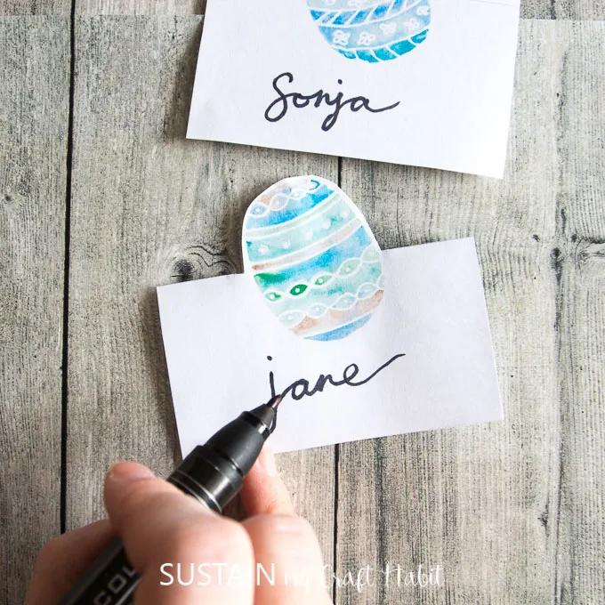 Hand lettering an Easter place card on a rustic wood background