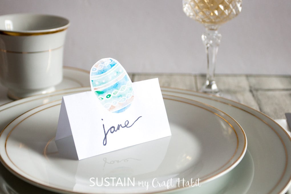 Beautiful Easter tablescape with gold rimmed plates and a printable Easter egg place card