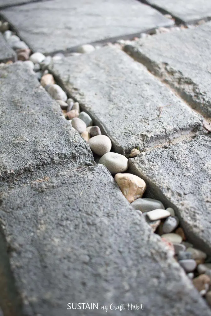 Close up image of beach pebbles between patio stones as the floor of the outdoor shower.
