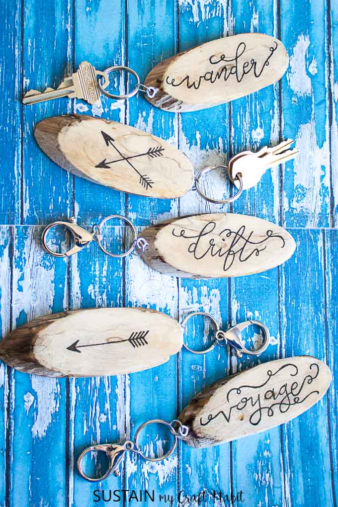 diy keychains with handlettering made from wood slices on a rustic blue backdrop