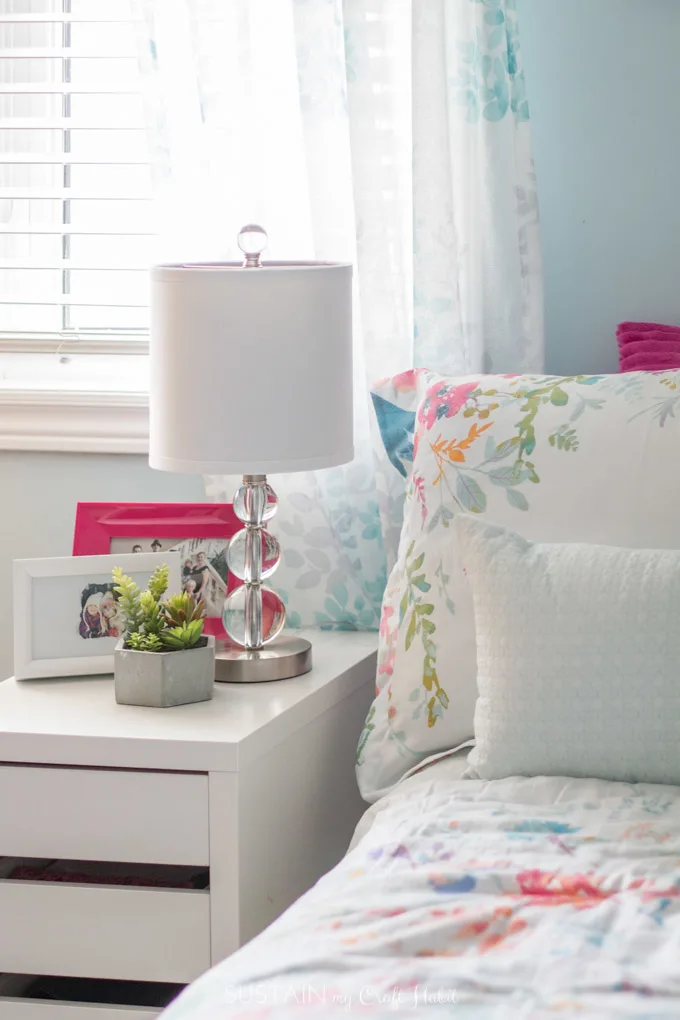 A crystal lamp with a white lampshade on a nightstand of a tween girl's bedroom