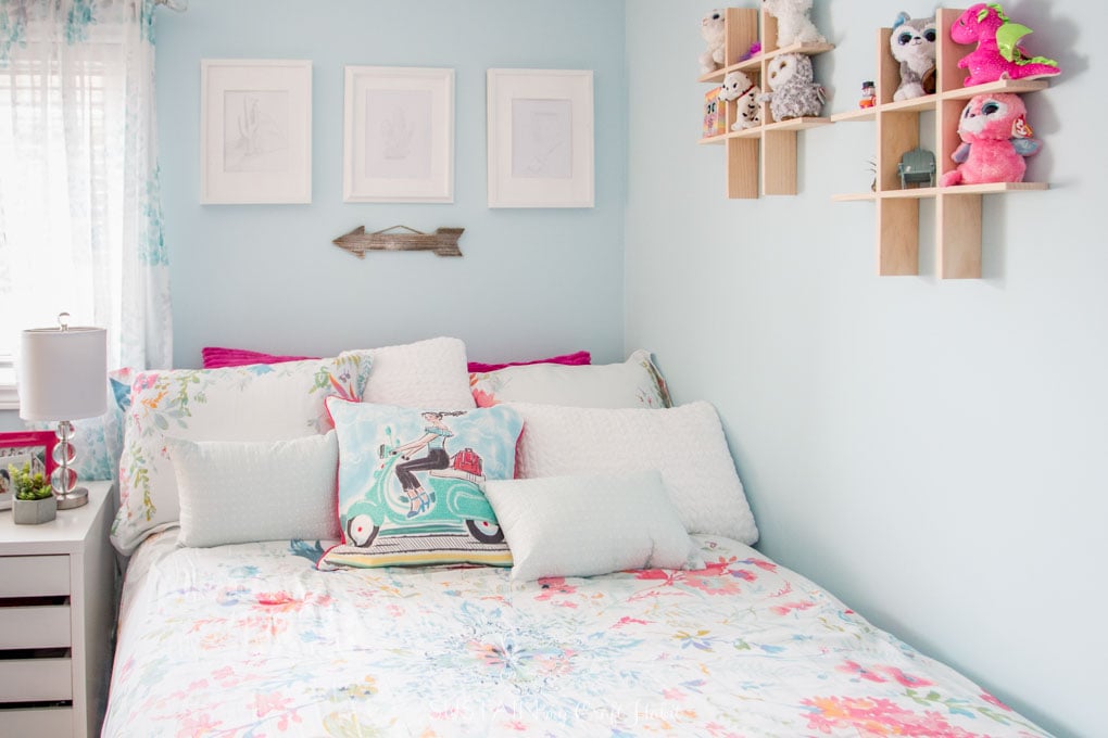 White, teal and pink throw pillows on a bed in a teal painted bedroom