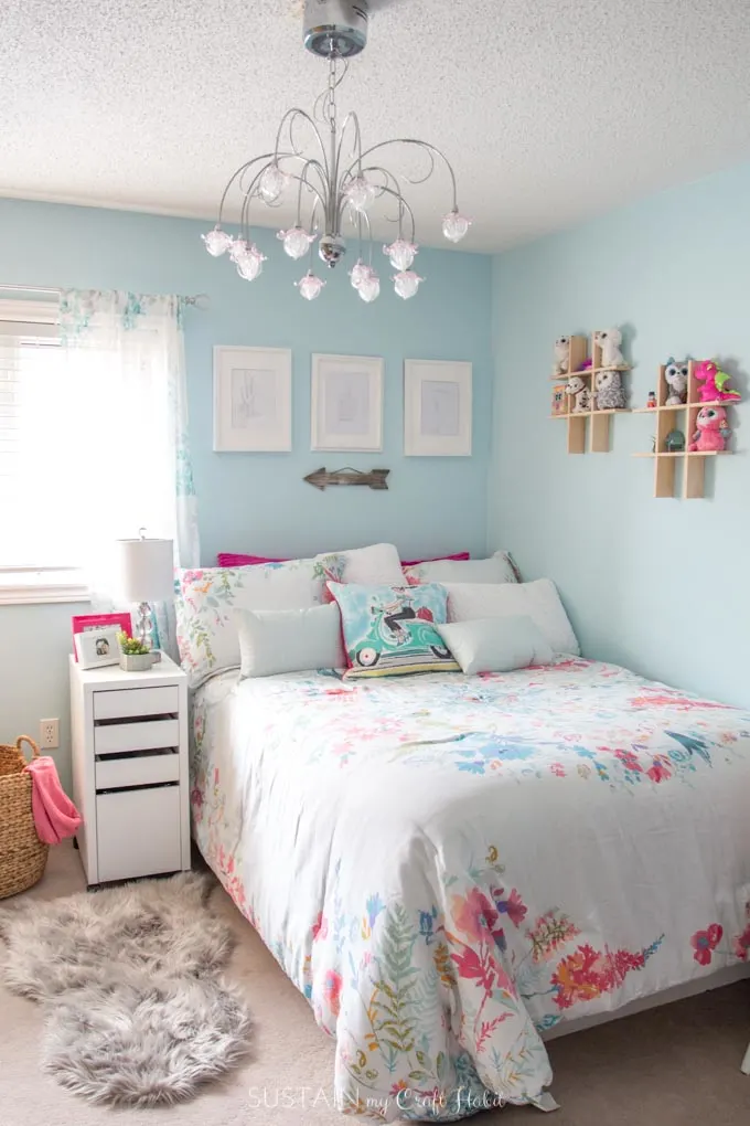 Bedroom with teal walls, chandelier and white and pink accessories