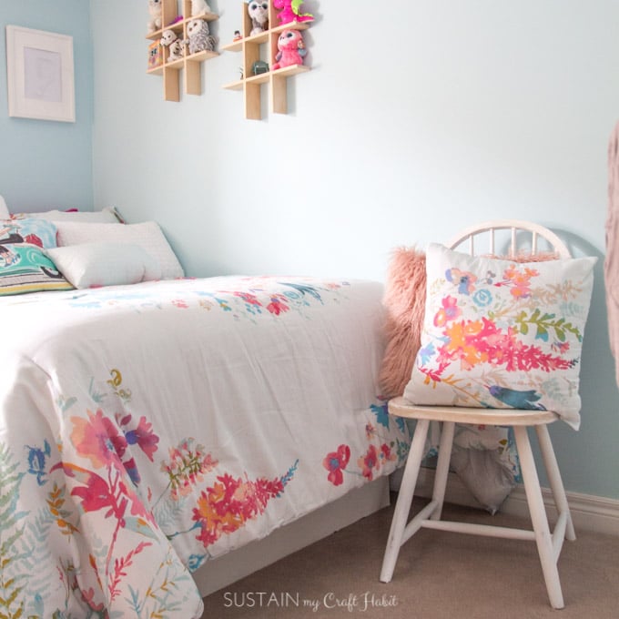 Wooden chair painted which with watercolor-inspired bedding in white, teals and pinks.