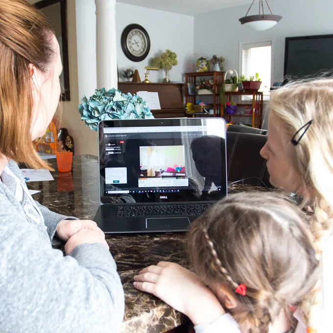 Woman and two children working at a kitchen table with a laptop