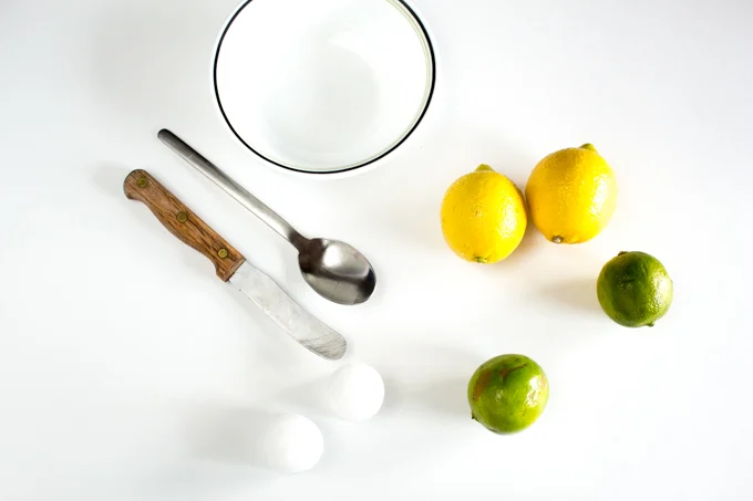 Lemons, limes, paraffin candles, bowl, knife and spoon to make DIY citrus candles