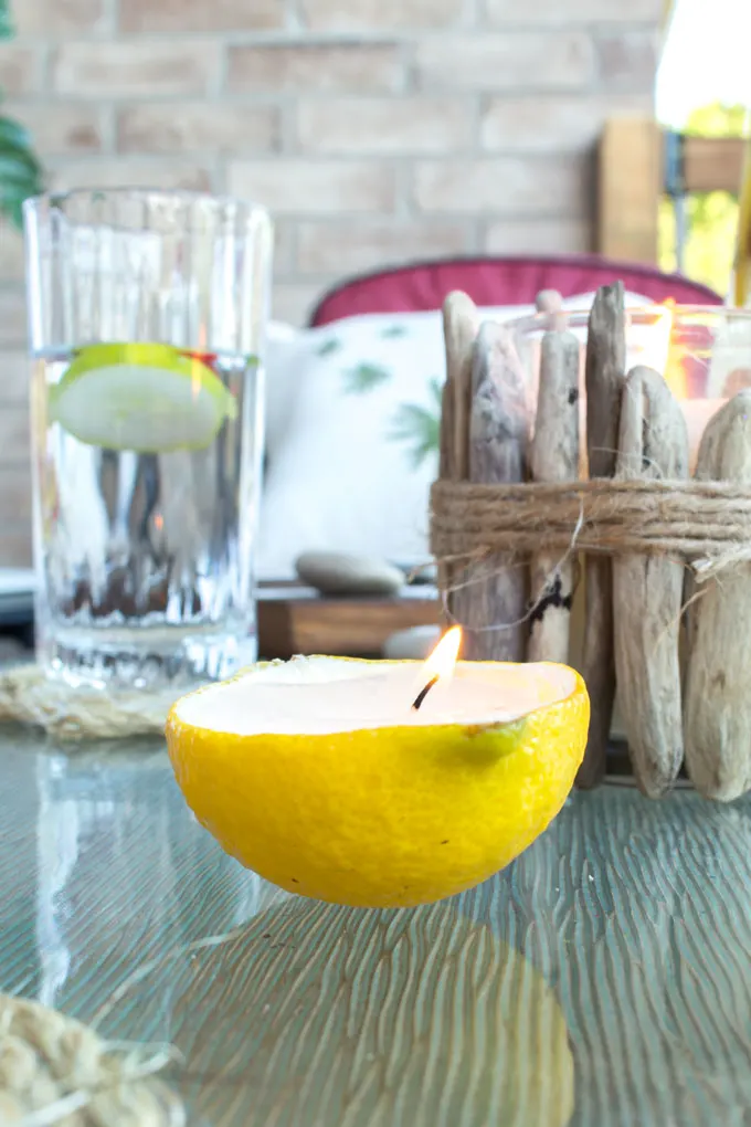 Lit candle made from a lemon rind on a glass outdoor patio table