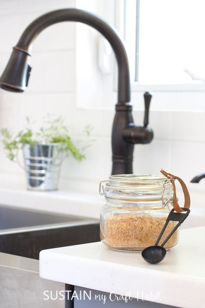 Glass jar of lavender sugar scrub on a white kitchen counter