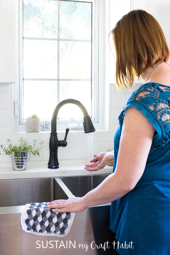 Standing at the sink of a coastal cottage kitchen featuring a faucet from Delta Faucet Canada's Cassidy collection