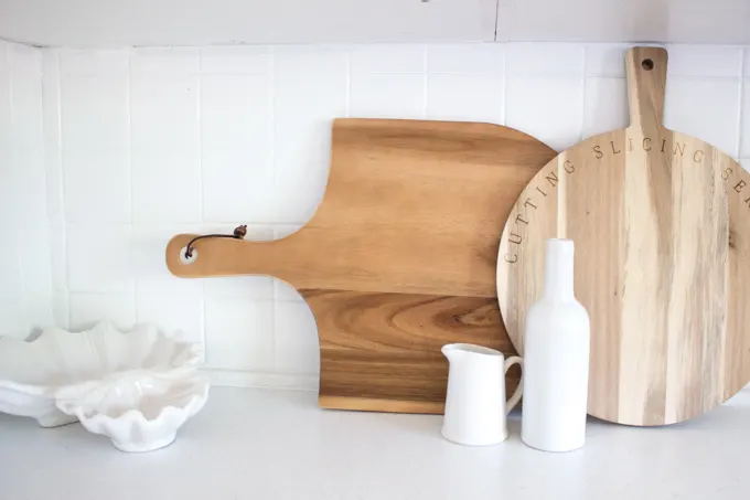 Kitchen tile backsplash painted white and styled with an assortment of wood cutting boards.