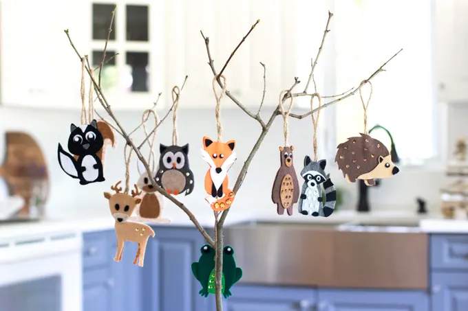 A small branch strung with woodland animal felt ornaments including a fox, owl, bear, racoon and more.