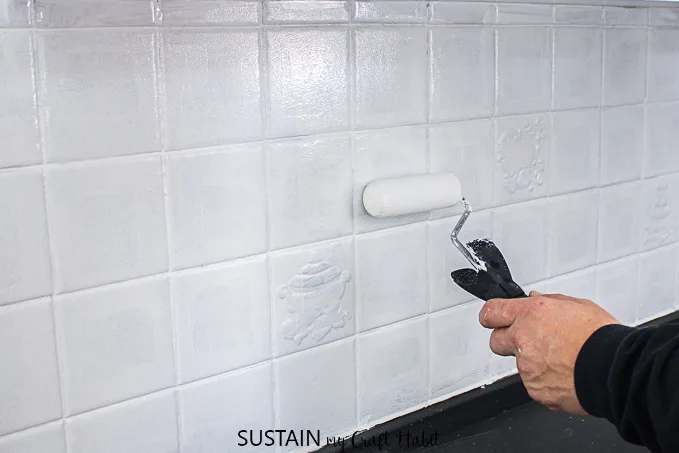 Applying a second coat of paint when painting a tile kitchen backsplash.