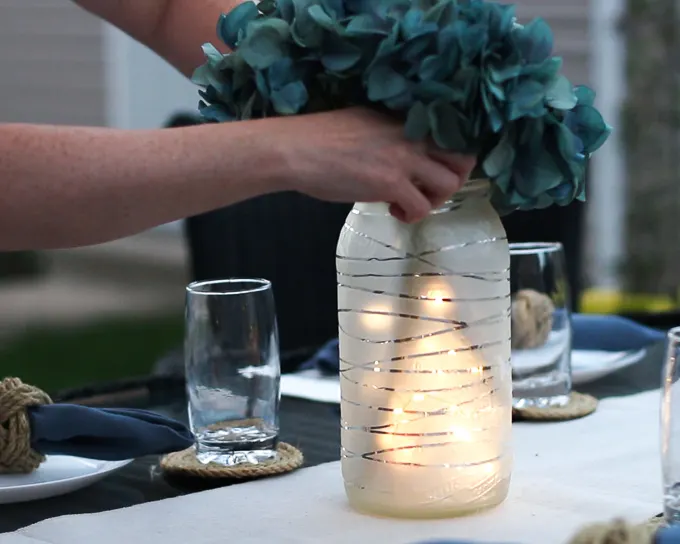 Placing faux florals into a frosted glass jar lantern