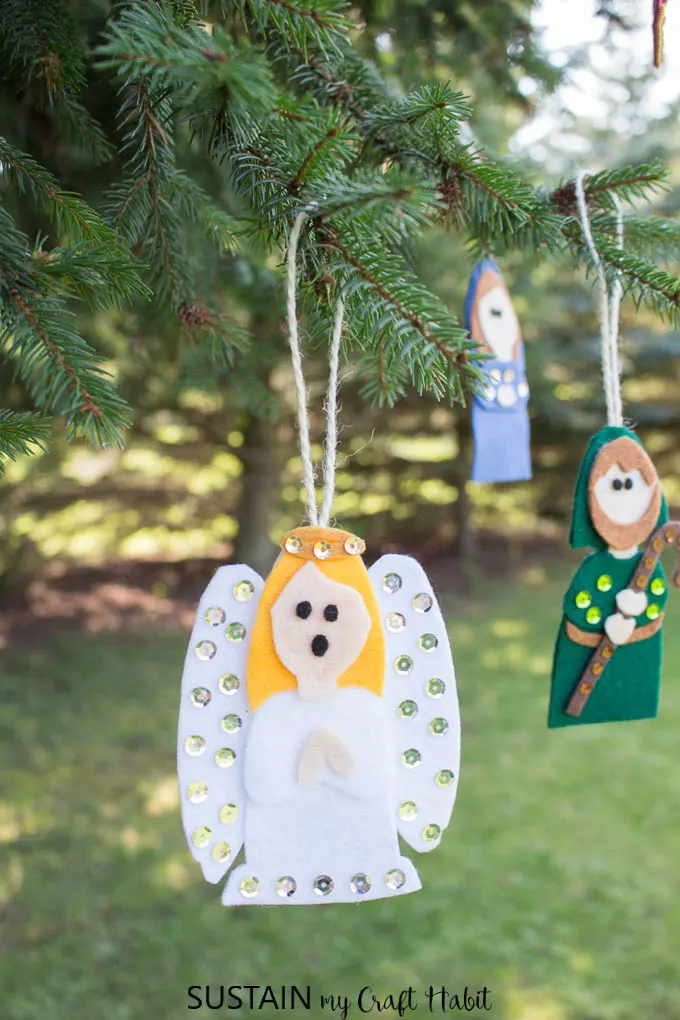 Felt Christmas ornaments including an angel and holy Joseph hanging from evergreen trees