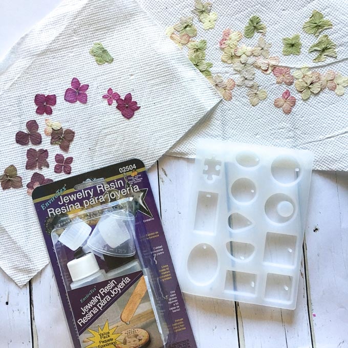 Overhead image of supplies needed to make resin jewelry including Envirotex Jewelry Resin, silicone mold and pressed, dried hydrangea flowers.