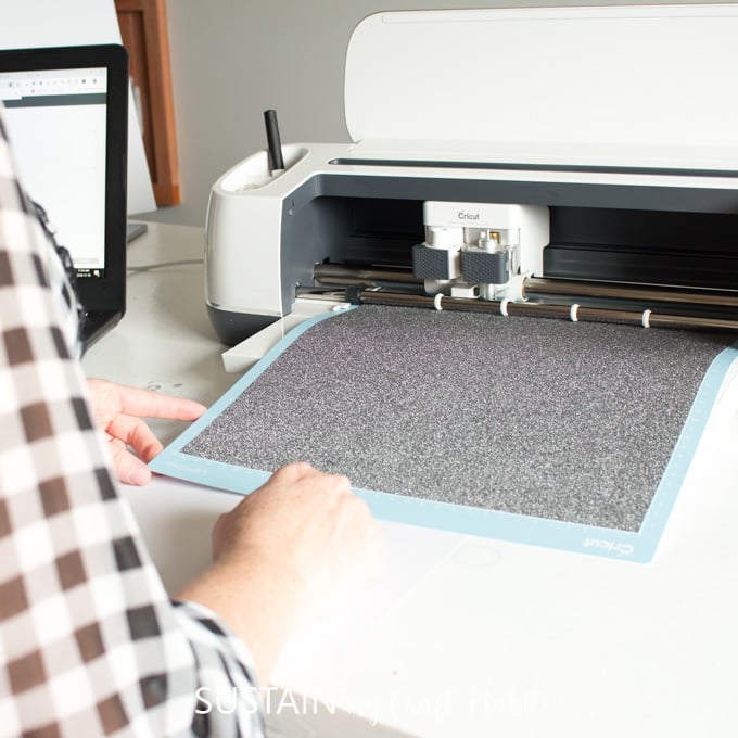 A Cricut Maker cutting black glitter adhesive vinyl for a rock crafts project